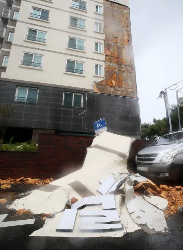 제8호 태풍 '바비'가 제주를 강타한 26일 오후 제주시 동광로 한 아파트 외벽 마감재가 떨어져 주차된 차량을 덮치고 있다. 연합뉴스