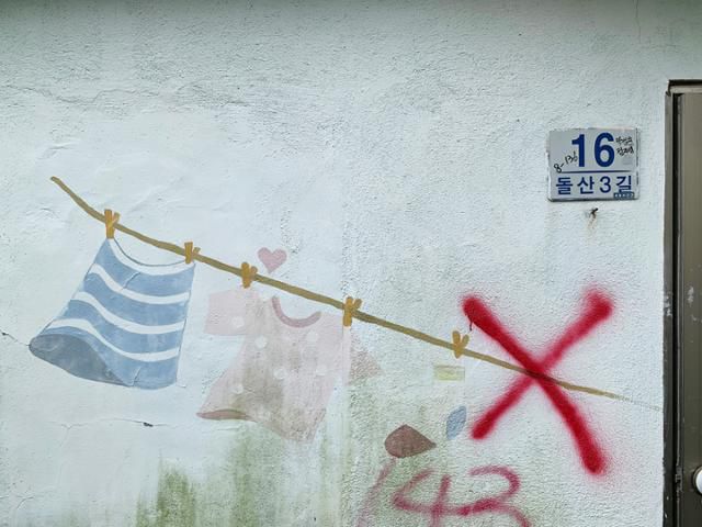 문현동 안동네 벽화마을에 그려진 빨랫줄 벽화. 퇴거 완료를 뜻하는 'X'자 표식이 겹쳐있다. 김시덕 제공