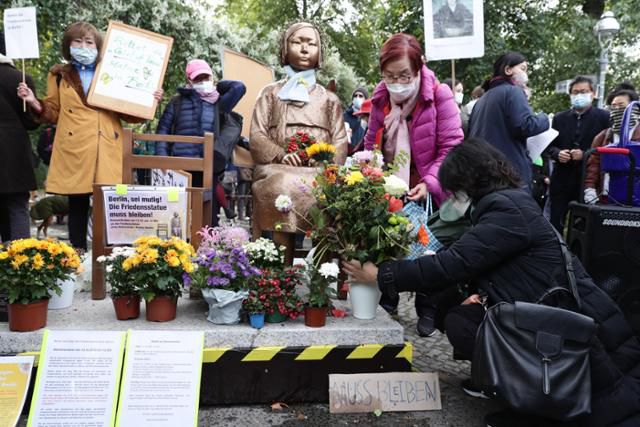 13일(현지시간) 독일 베를린 미테구 소녀상 앞에서 독일 당국의 소녀상 철거 지시의 부당함을 주장하는 항의 시위가 열린 가운데 한 시민이 소녀상 앞에 꽃을 놓고 있다. 베를린=EPA 연합뉴스