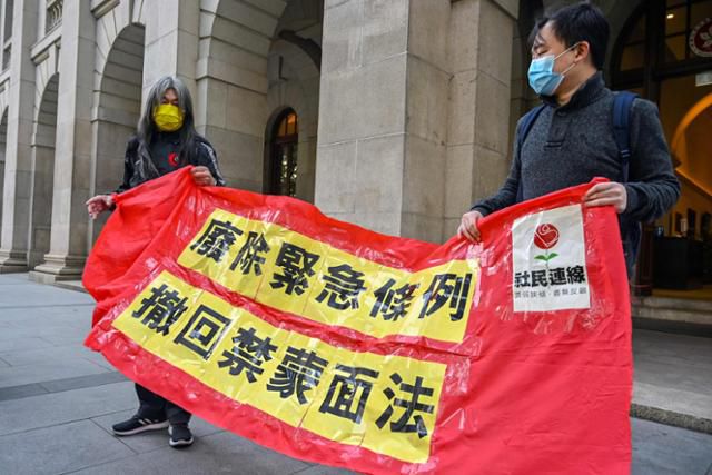 홍콩 야권 정치인 렁쿽헝(왼쪽)이 21일 종심법원 앞에서 '긴급법 철폐 복면금지법 철회'라는 문구가 적힌 현수막을 들고 1인 시위를 하고 있다. 홍콩=AFP 연합뉴스