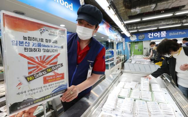 일본 정부가 후쿠시마 제1원전 오염수를 바다에 방류하기로 결정한 13일 서울 도봉구 하나로마트 창동점 수산물 코너에서 직원이 '일본산 수산물을 판매하지 않는다'는 안내문을 붙이고 있다.