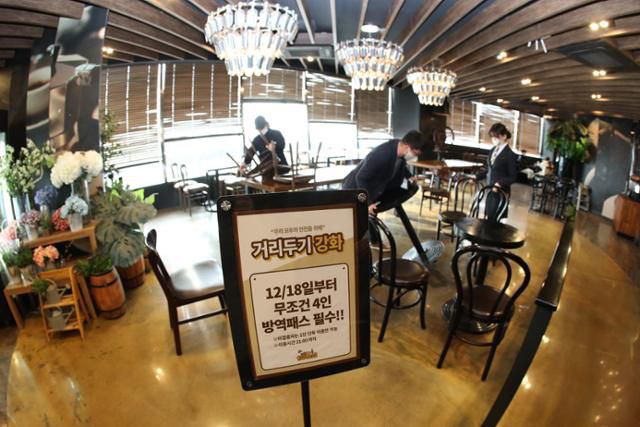 국내 신종 코로나바이러스 감염증(코로나19) 확산으로 방역에 비상이 걸린 가운데 16일 오후 대구 달서구 이월드 83타워 내부 한 카페에서 직원들이 테이블을 재배치하고 있다. 입구에는 거리두기 강화 안내문이 붙어 있다. 대구=뉴스1