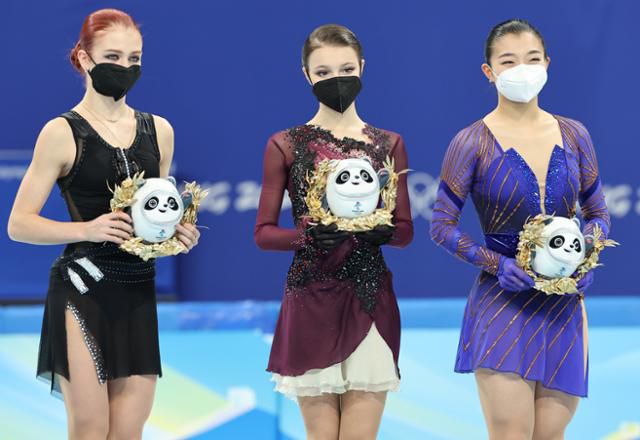 17일 중국 베이징 캐피털 실내경기장에서 열린 2022 베이징 동계올림픽 피겨스케이팅 여자 싱글 프리스케이팅이 끝난 뒤 1~3위를 차지한 선수들이 링크 내에 설치된 시상대에 올라 기념촬영을 하고 있다. 왼쪽부터 은메달 러시아올림픽위원회(ROC) 알렉산드라 트루소바, 금메달 ROC 안나 셰르바코바, 동메달 일본의 사카모토 가오리. 트루소바가 마스코트 인형 빙둔둔을 들고 있는 모습에서 손가락 욕설 논란이 불거졌다. 베이징=연합뉴스