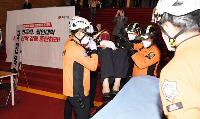 국민의힘 양금희 의원이 30일 국회 본회의장에서 고통을 호소해 출동한 구급대원에 의해 후송되고 있다. 양 의원은 앞서 국회의장실 앞에서 농성하며 박의장의 입장을 제지하는 과정에서 부상을 입게 되었다. 뉴시스