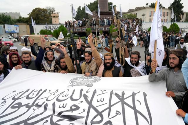 15일 탈레반 대원들이 아프가니스탄 카불의 옛 미국대사관 건물 앞에서 아프간 재점령 1주년을 자축하며 깃발을 흔들고 있다. 카불=AP 연합뉴스