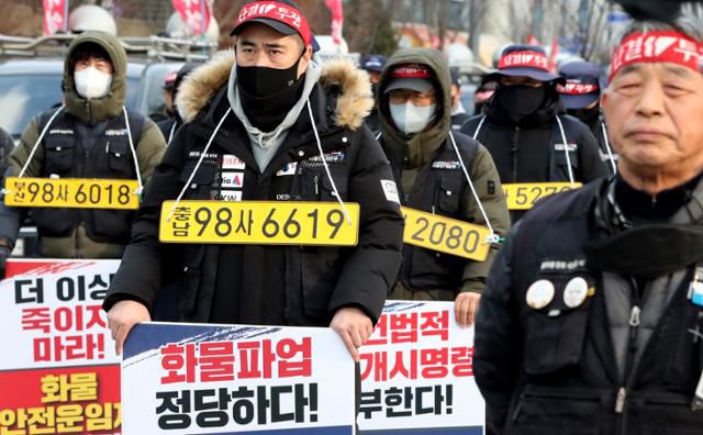 7일 오후 세종시 정부세종청사 국토교통부 앞에서 열린 민주노총 공공운수노조 화물연대본부 집회에서 노조원들이 화물차 번호판을 목에 걸고 정부의 업무개시명령을 규탄하며 안전운임제 일몰제 폐지 등을 요구하고 있다. 세종=뉴스1