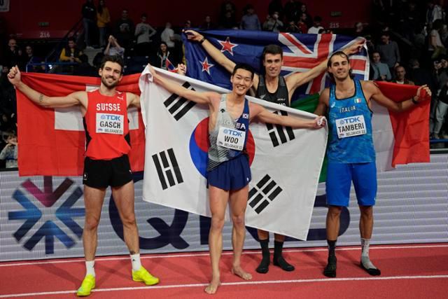 우상혁(왼쪽 두 번째)이 3월 20일(현지시간) 세르비아 베오그라드의 스타크 아레나에서 열린 2022 세계실내육상선수권대회 남자 높이뛰기에서 우승한 후 태극기를 두르고 포즈를 취하고 있다. AP 뉴시스