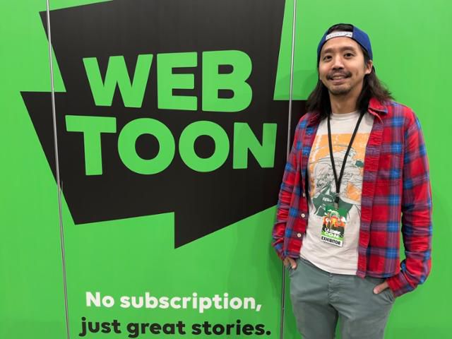 지난해 12월 3일(현지시간) 미국 캘리포니아 로스앤젤레스 'LA 코믹콘'에 설치된 네이버웹툰 부스에서 이신옥 네이버웹툰 북미사업 콘텐츠 총괄 리더가 웹툰 로고를 배경으로 활짝 웃고 있다. 로스앤젤레스=이서희 특파원