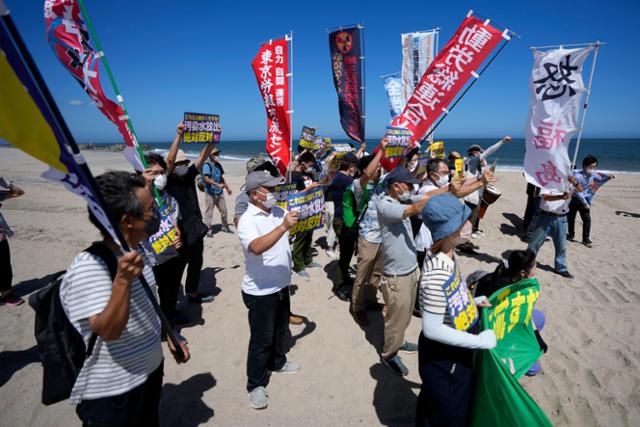 24일 일본 후쿠시마현 나미에마치의 해변에서 시위대가 후쿠시마 제1원자력발전소 쪽을 바라보며 오염수 방류 반대 시위를 하고 있다. 도쿄전력은 이날 오후 1시부터 오염수 방류를 시작했다. 나미에(후쿠시마현)=AP 뉴시스