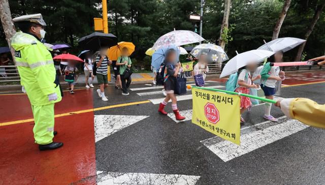 교통지도원 등의 수신호에 맞춰 안전하게 횡단보도를 건너는 서정초 학생들의 모습. 뉴스1