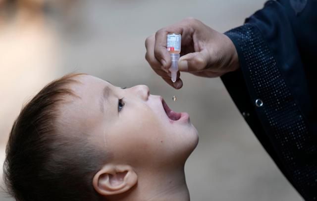지난달 파키스탄 카라치에서 한 보건 종사자가 아프가니스탄 난민 어린이에게 소아마비 백신을 투여하고 있다. AP
