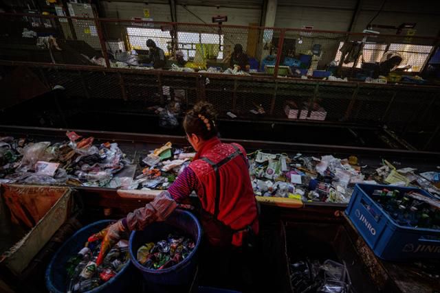 수도권의 한 자원순환센터에서 작업자들이 컨테이어 벨트 위로 흐르는 폐기물 가운데 재활용품을 선별하고 있다.
