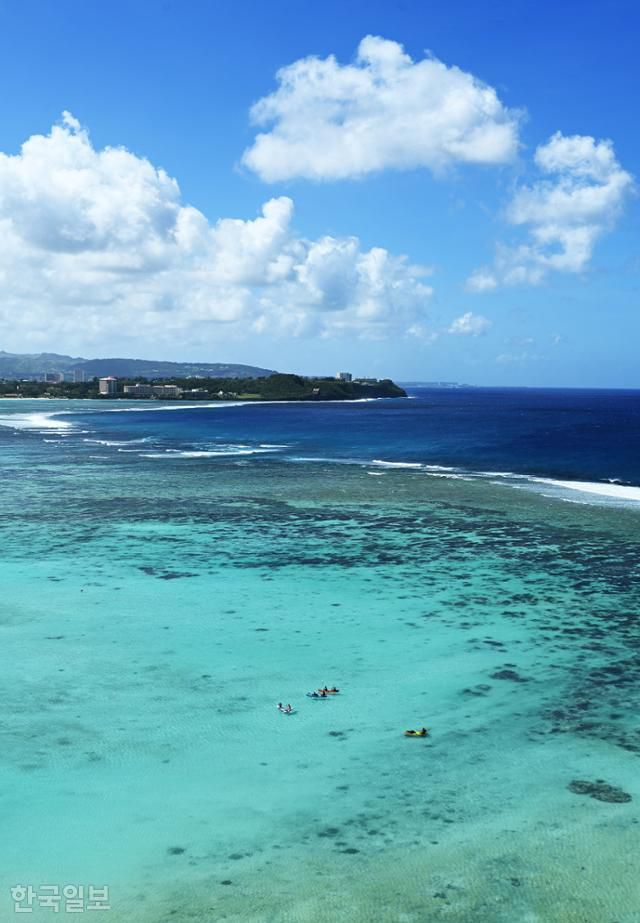 괌 여행의 중심 투몬비치에서 여행객들이 보트놀이를 즐기고 있다. 바깥 바다에는 파도가 들이치지만, 얕은 안쪽 바다는 투명하고 잠잠하다.