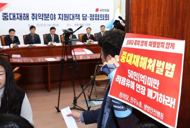 고 김용균씨 어머니 김미숙씨가 지난해 12월 27일 서울 여의도 국회에서 열린 중대재해 취약분야 지원대책 관련 당정협의회 회장 앞에서 중대재해처벌법 적용유예연장 폐기 손 피켓을 들고 있다. 뉴스1