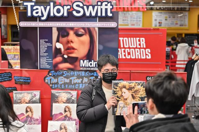 미국 팝스타 테일러 스위프트의 공연을 하루 앞둔 지난 6일 일본 도쿄에서 한 시민이 공연 포스터를 배경으로 사진을 찍고 있다. 도쿄=AFP 연합뉴스