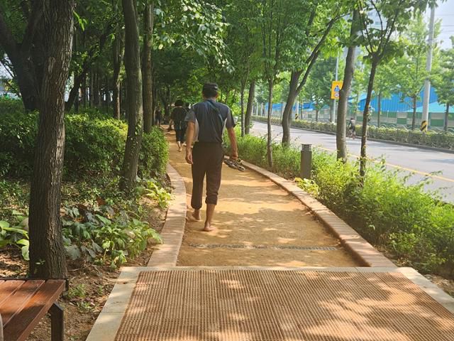 12일 서울 동대문구 이문동에 마련된 황톳길에서 시민들이 신발을 벗고 맨발로 걷고 있다. 윤한슬 기자