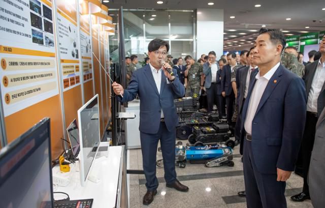 신원식 국방부 장관이 3일 서울 용산구 국방부 청사 1층 로비에 마련된 국방 데이터·인공지능 분야 주요 성과물 전시 공간을 찾아 곽기호 국방AI센터장의 설명을 듣고 있다. 국방부 제공