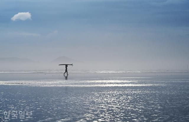 한 서퍼가 바닷물이 찰랑거리는 다대포해수욕장을 가로지르고 있다. 수시로 해무가 올라 몽환적인 분위기를 자아낸다.