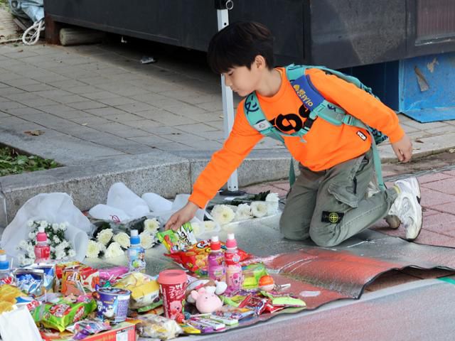 지난 31일 광주 북구 신용동 한 아파트에서 한 학생이 재활용품 수거 차량에 치여 숨진 초등생을 추모하기 위해 과자를 놓고 있다. 연합뉴스