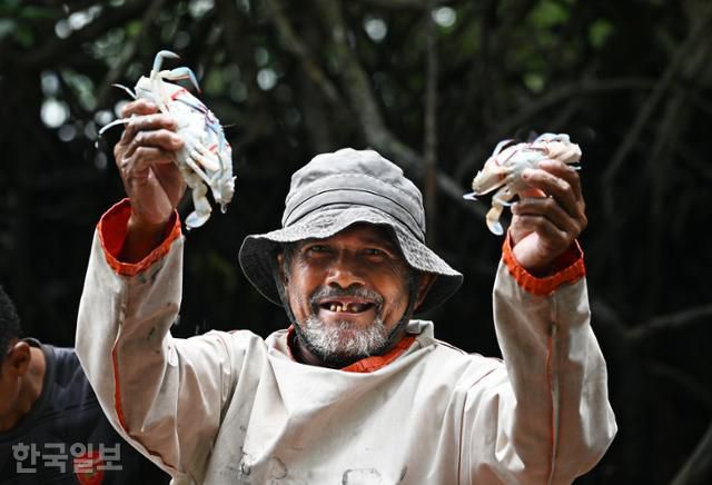 발레발레 원주민 마을의 어부가 맹그로브숲에서 잡은 게를 자랑하고 있다.