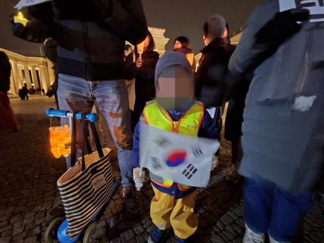 4세 남아가 부모와 함께 13일 독일 베를린 브란덴부르크문에서 열린 윤석열 대통령 탄핵 촉구 집회에 참가하고 있다. 베를린=신은별 특파원