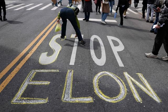 지난달 22일 미국 뉴욕에서 일론 머스크 테슬라 최고경영자(CEO)를 상대로 한 '테슬라 테이크다운' 집회에서 시위 참가자들이 시위를 벌이고 있다. 뉴욕=AFP 연합뉴스