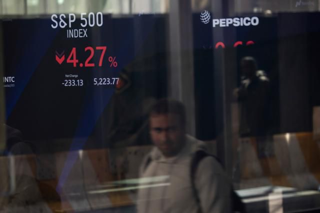 미국과 중국 간 '관세 전쟁' 여파로 뉴욕 증시가 폭락한 10일 한 남성이 뉴욕증권거래소 전광판 인근을 지나가고 있다. 뉴욕=AP 연합뉴스