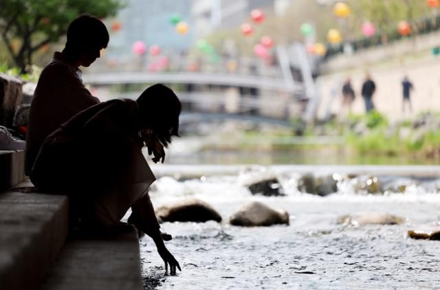 초여름 날씨를 보인 18일 서울 중구 청계천에서 한 시민이 손을 물에 넣고 있다. 연합뉴스