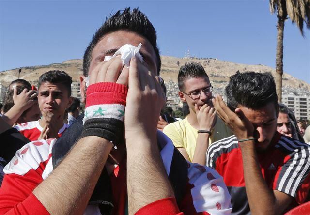 2017년 7월 시리아 수도 다마스쿠스에 모인 시리아 국민들이 자국대표팀의 러시아월드컵 본선행 진출 실패에 눈물을 흘리며 아쉬워하고 있다. 당시에도 시리아는 호주와 월드컵 아시아지역 최종예선 플레이오프 홈경기(1차전)를 말레이시아에서 치러야 했다. 다마스쿠스=AFP 연합뉴스