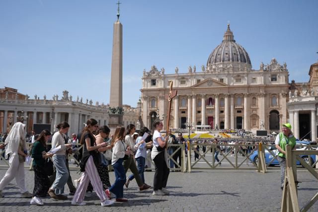 프란치스코 교황이 선종한 21일 바티칸의 성베드로 광장에서 신자들이 십자가를 들고 이동하고 있다. 바티칸=AP 뉴시스