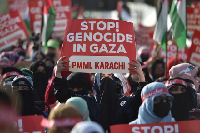 파키스탄 카라치에서 열린 이슬람 정당 '파키스탄 마르카지 무슬림 리그' 지지자들의 시위에서 한 참여자가 가자지구에서의 학살을 멈추라라는 뜻의 피켓을 들고 있다. 카라치=EPA 연합뉴스