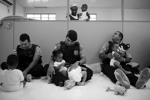 전투화와 방탄복을 착용한 경찰들이 2010년 브라질 리우데자네이루의 한 보육원에서 아기들을 돌보고 있다. 시는 경찰들이 빈민가 단속을 하다 아이들을 향해 총을 쏘는 일이 빈번하게 발생하자 이에 대한 대책으로 빈민가 보육원에 가서 아이들을 돌보도록 했다. 에이도스 제공