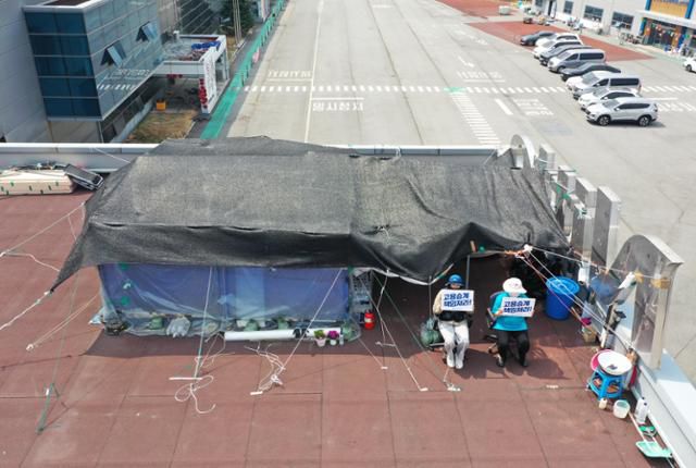 10일 경북 구미시 한국옵티칼하이테크 고공농성장에서 박정혜(왼쪽), 소현숙 노동자가 손팻말을 들고 있다. 구미=홍인기 기자