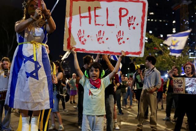 한 아이가 지난 10일 이스라엘 텔아비브에서 베냐민 네타냐후 총리에게 팔레스타인 무장 정파 하마스에 억류된 인질들을 석방하기 위한 협상에 적극적으로 참여할 것을 요구하는 시위에 참석하고 있다. 텔아비브=로이터 연합뉴스