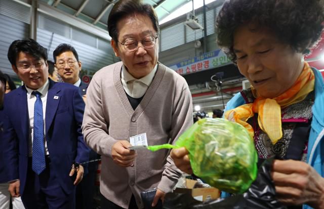 이재명 더불어민주당 대선 후보가 제3차 골목골목 경청투어로 경북지역 방문에 나선 지난 9일 경북 영천시 영천공설시장을 찾아 한 가게에서 영천사랑상품권으로 말린 고추를 구매하고 있다. 연합뉴스