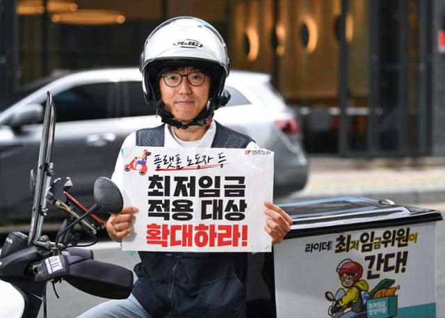 제13대 최저임금위원회 근로자 위원인 박정훈 민주노총 공공운수노조 부위원장이 지난해 6월 7일 서울 중구 한국일보 사옥 앞에서 플랫폼 노동자 등에게도 최저임금을 확대 적용할 것을 촉구하는 피켓을 들고 있다. 임은재 인턴기자