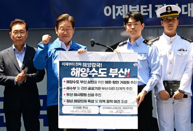 이재명 더불어민주당 대통령 후보가 14일 부산 부산진구 서면 젊음의 거리에서 권기흥 에이치라인해운해상직원노조 위원장과 해양수도 부산 협약서에 서명한 뒤 들어보이고 있다. 부산=고영권 기자