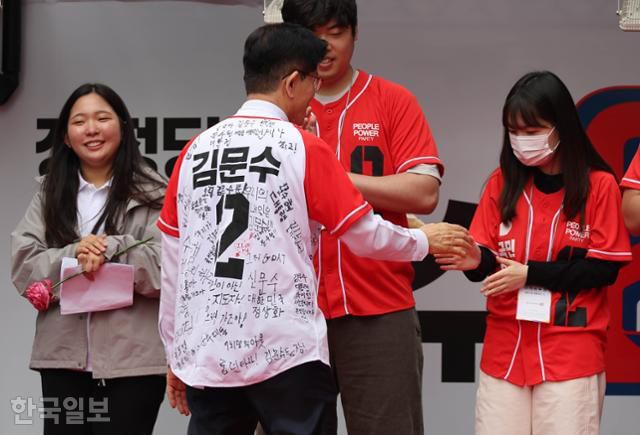 김문수 국민의힘 대선 후보가 19일 서울 중구 청계광장에서 청년들의 응원 메시지가 적힌 옷을 입고 청년들과 인사하고 있다. 하상윤 기자