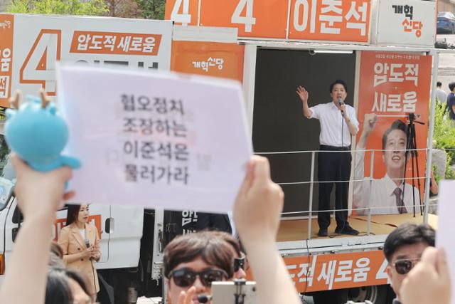 이준석 개혁신당 대선 후보가 30일 서울 동작구 중앙대 후문에서 유세차에 올라 연설하는 도중 일부 학생들이 이 후보를 규탄하는 손팻말을 들어 보이고 있다. 연합뉴스