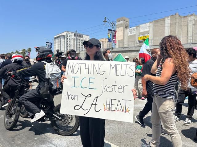 8일 미국 캘리포니아주 로스앤젤레스 메트로폴리탄 디텐션 센터 앞에서 멕시코계 미국인인 애나가 'LA의 더위만큼 얼음을 빨리 녹이는 건 없다'고 적힌 팻말을 들고 이민세관단속국(ICE)의 불법 이민자 검거 작전에 항의하고 있다. 이민세관단속국의 약자와 '얼음'이란 뜻의 영단어(ice) 철자가 같은 것을 이용한 문구다. 로스앤젤레스=이서희 특파원