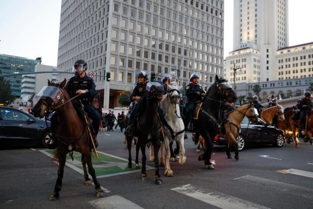 미국 캘리포니아주 로스앤젤레스 도심 일부 지역에 통행금지령이 발효된 10일 말을 탄 경찰들이 도로 통행을 막아서고 있다. 로스앤젤레스=EPA 연합뉴스