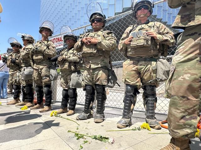 14일 미국 캘리포니아주 로스앤젤레스 시청 일대에 주방위군이 주둔해 있다. 군인들 앞에 비폭력 저항과 평화를 상징하는 꽃이 놓여 있다. 시위대가 둔 것이다. 로스앤젤레스=이서희 특파원