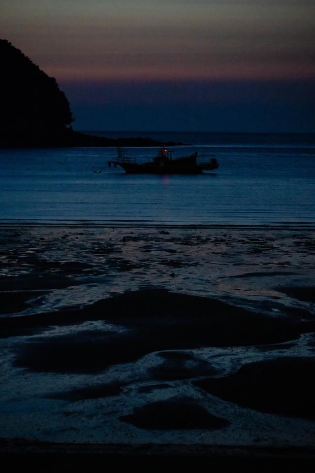 밤이 내린 대이작도의 갯벌 뒤로 작은 어선이 떠 있다.