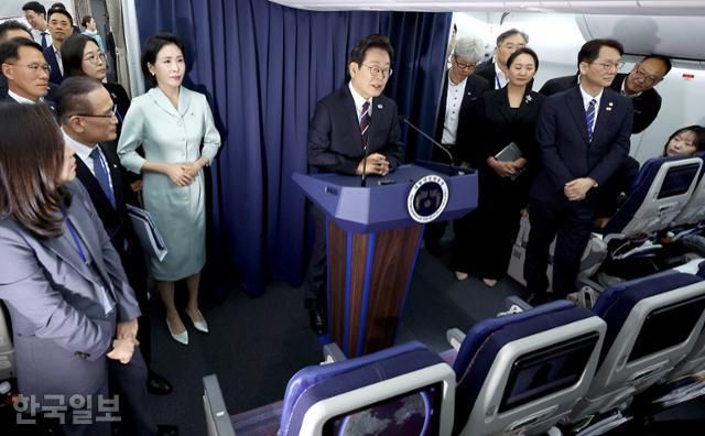 이재명 대통령이 16일 G7 정상회의 참석을 위해 캐나다 캘거리로 향하는 공군 1호기 기내에서 기자회견을 하는 동안 김혜경 여사가 한발짝 뒤에서 손을 모은채 이대통령의 발언을 듣고 있다. 왕태석 선임기자