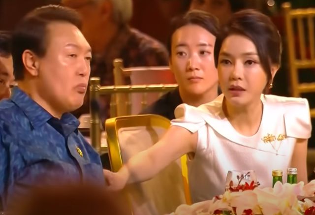 2022년 11월 15일 인도네시아 발리에서 열린 주요 20개국(G20) 정상회의 환영 만찬 행사 도중 김건희(오른쪽)씨가 윤석열(왼쪽) 전 대통령에게 손짓을 하고 있다. 자리에서 일어나 타국 정상들과 대화하라는 의미였던 것으로 해석됐다. 유튜브 YTN 채널 캡처