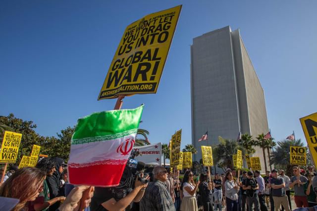 18일 미국 캘리포니아주 로스앤젤레스 윌셔 연방 빌딩 밖에서 미국의 대이란 전쟁에 반대하는 시위대가 구호가 적힌 팻말과 이란 국기들 든 채 집회를 열고 있다. 로스앤젤레스=AFP 연합뉴스