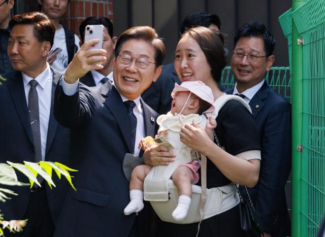 당시 이재명 더불어민주당 대통령 후보가 제21대 대통령선거 사전투표 첫날인 지난달 29일 서울 서대문구 구 신촌동주민센터에서 청년들과 사전투표를 마친 뒤 아이를 안은 주민과 셀카를 찍고 있다. 뉴스1