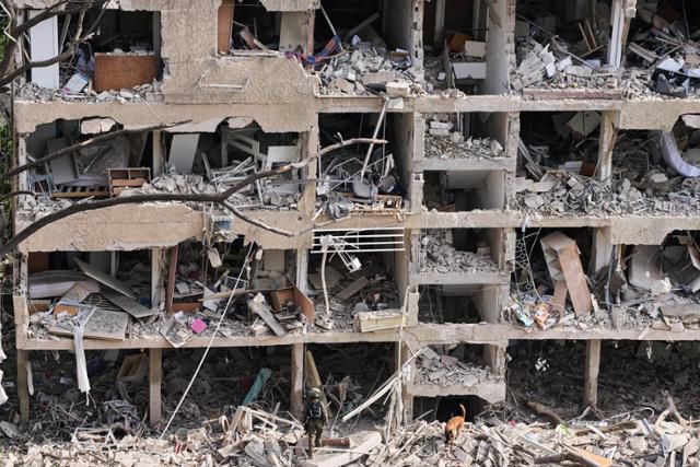 이스라엘 텔아비브에 21일 이란 미사일이 떨어지면서 파괴된 건물에서 구조대원들이 구조 작업을 진행하고 있다. 텔아비브=AP 연합뉴스