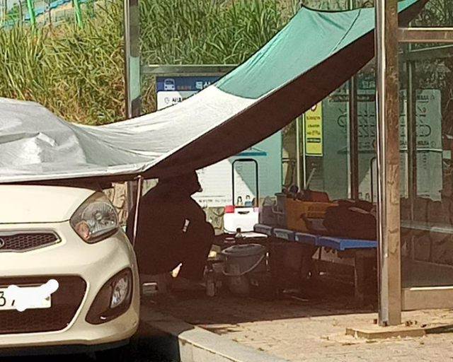 그늘막 밑 여성 앞에 해루질에 쓰이는 장비가 나열돼 있다. 보배드림 캡처