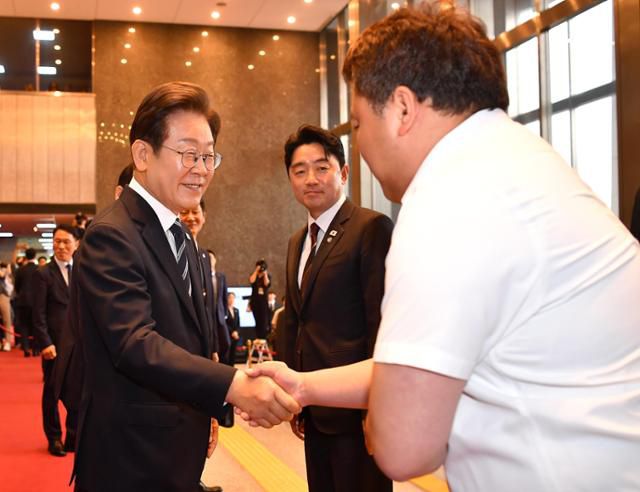 이재명(왼쪽) 대통령이 26일 서울 여의도 국회에서 추가경정예산 시정연설을 마친 뒤 의사당을 나서며 한 국회 직원(오른쪽)과 악수하고 있다. 가운데는 강훈식 대통령 비서실장. 뉴시스